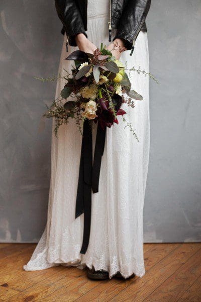 Brautkleid mit Lederjacke und Brautstrauß opulenter Brautstrauß mit Rosen und Blattgrün